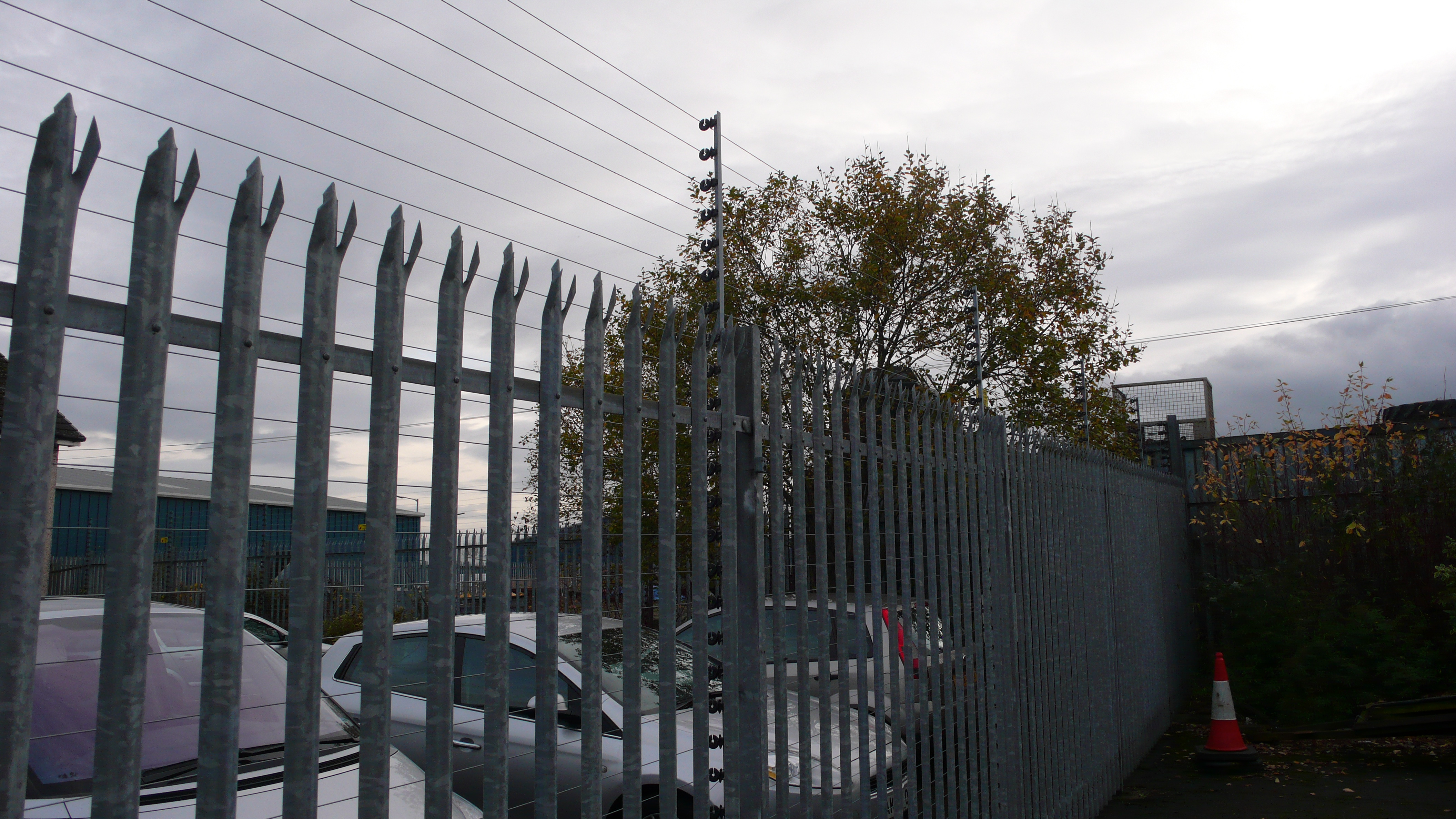 Palisadenzaun mit Elektrodraht an Fahrzeug-Stellplatz